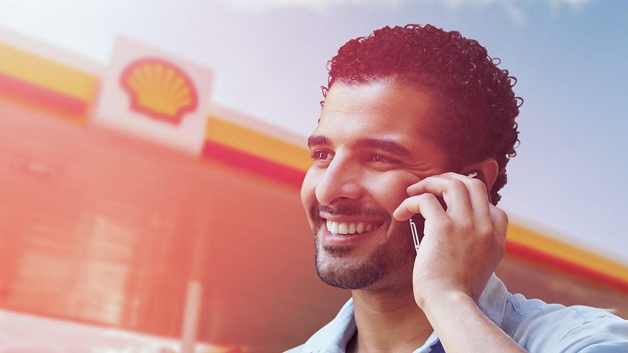 homme tunisien en ligne avec son telephone mobile dans une station Shell