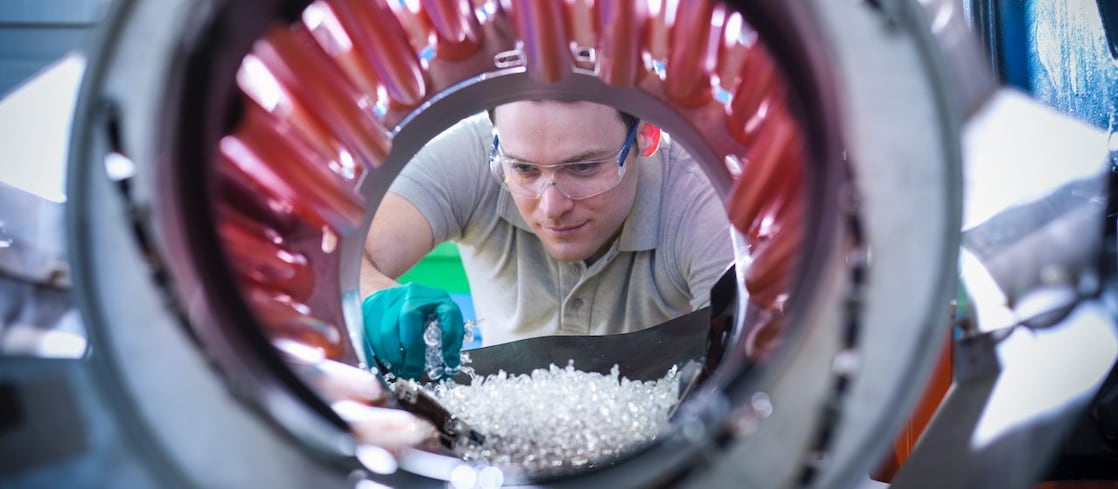 Un homme transvase des granules de plastique pour les mettre dans un malaxeur