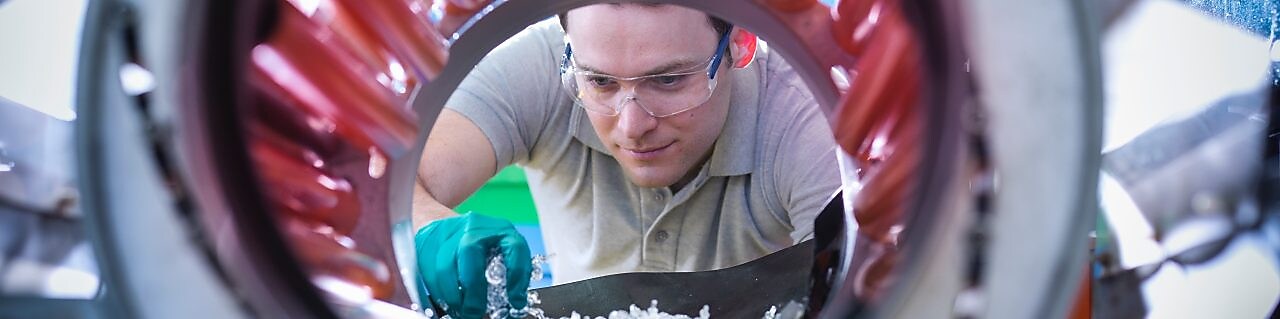 Un homme transvase des granules de plastique pour les mettre dans un malaxeur