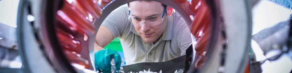 Un homme transvase des granules de plastique pour les mettre dans un malaxeur
