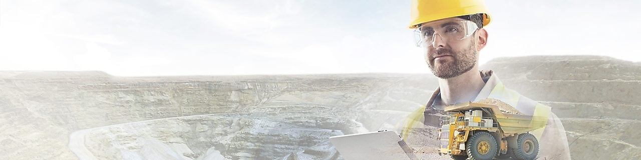 Travailleur portant un casque jaune transposé sur un fond de falaises et un gros camion jaune