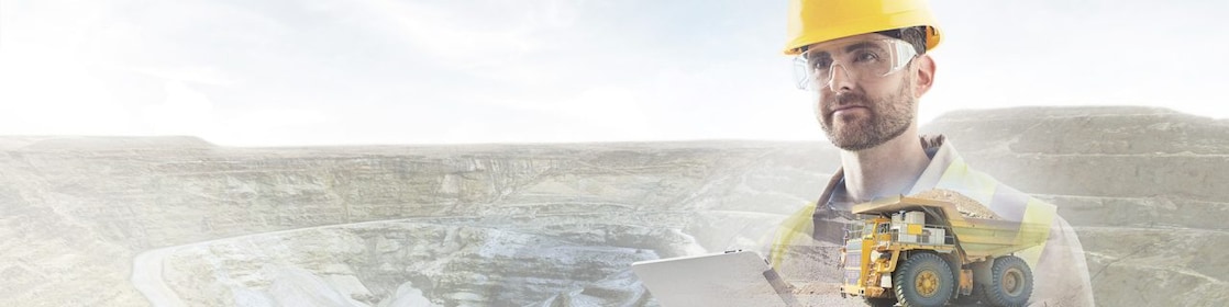 Travailleur portant un casque jaune transposé sur un fond de falaises et un gros camion jaune