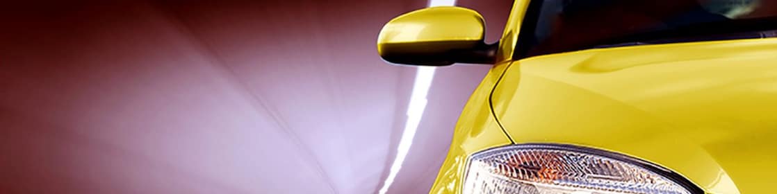 Avant d'une voiture jaune roulant dans un tunnel, phare avant droit et rétroviseur visibles