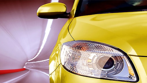 Avant d'une voiture jaune roulant dans un tunnel, phare avant droit et rétroviseur visibles