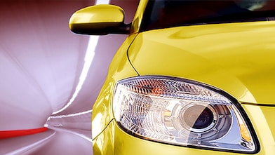 Avant d'une voiture jaune roulant dans un tunnel, phare avant droit et rétroviseur visibles