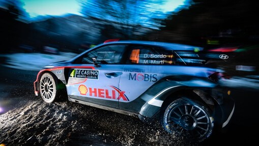 Une voiture de rallye fonce à la tombée de la nuit sur une épreuve du championnat du monde des rallyes