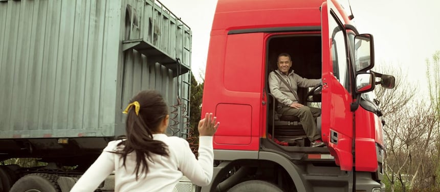 Homme dans une cabine de camion rouge avec porte ouverte saluant sa fille