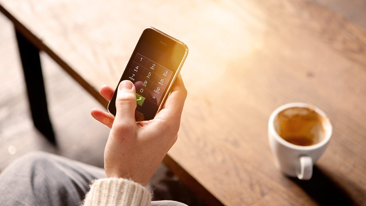 Homme tenant un téléphone portable et buvant un café