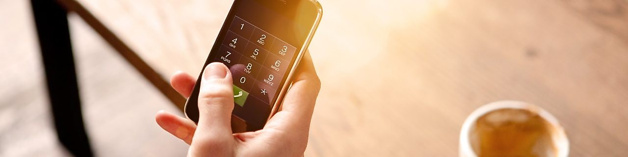 Homme tenant un téléphone portable et buvant un café