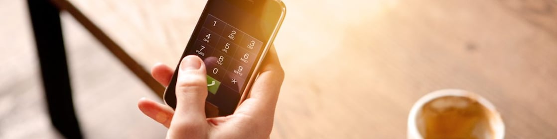 Homme tenant un téléphone portable et buvant un café